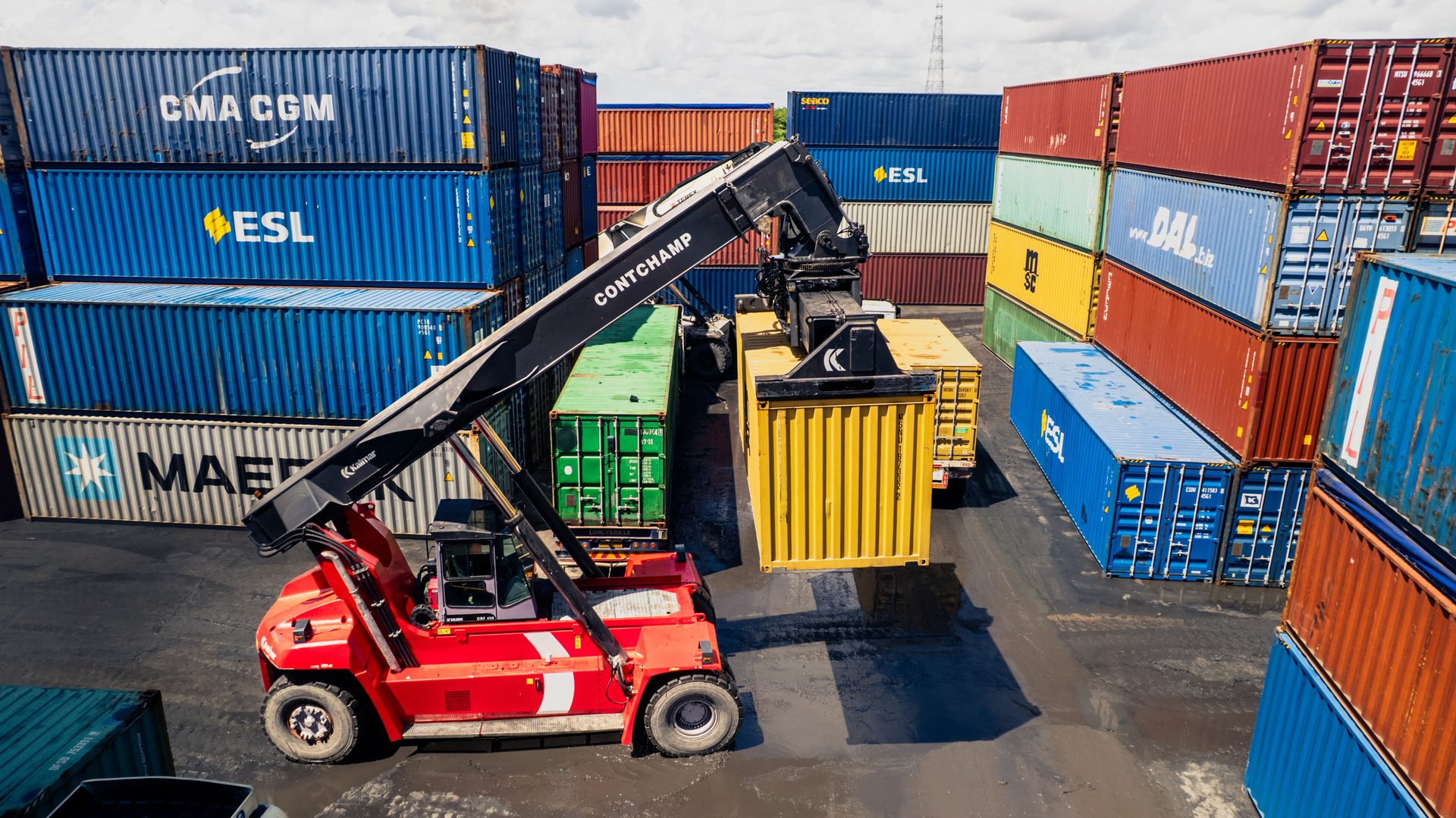 Contenedor siendo manipulado por una grúa reach stacker en patio de contenedores